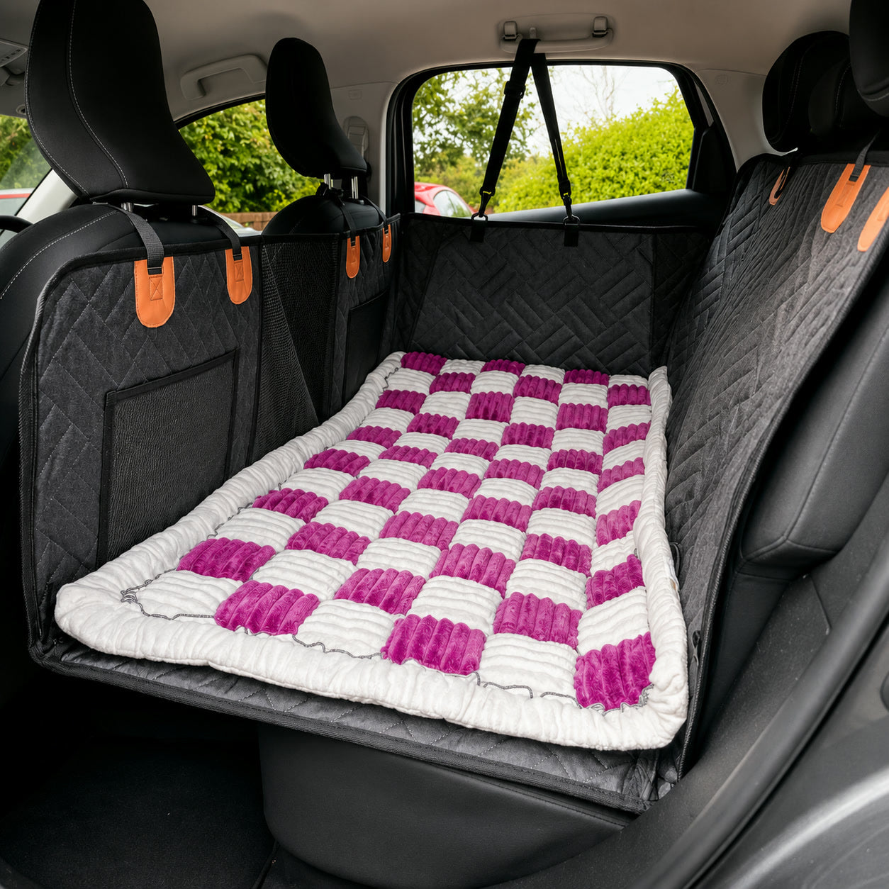 Pink checkerboard Luxe Dog Bed on a car back seat